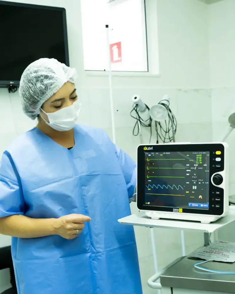 Assistente acompanhando os dados do paciente no monitor durante o procedimento